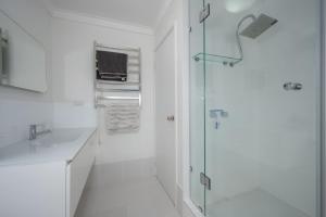a white bathroom with a shower and a glass door at The Whitehouse - South Yunderup in South Yunderup +21 photos