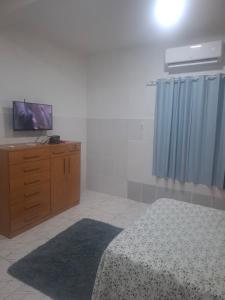 a bedroom with a bed and a tv on a dresser at Kitnet temporada in Belém