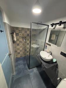 a bathroom with a glass shower and a sink at Candolim apartment in Candolim