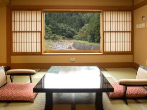 福島市にあるはるみや旅館のテーブルと椅子2脚と窓のある部屋