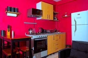 a red kitchen with a stove and a table at Comfortable modern studio villa in Castries