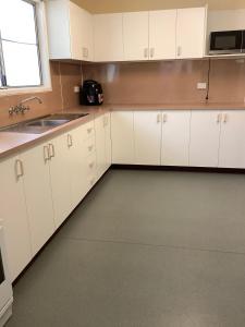 a kitchen with white cabinets and a sink and a window at Quiet, Charming 3BR in Moranbah