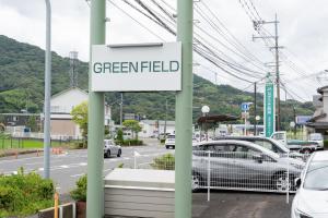 ein Schild für einen Parkplatz auf einer unbebauten Fläche mit geparkten Autos in der Unterkunft Green Field in Sasebo