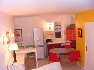 una pequeña cocina con mesa y sillas rojas en Résidence Espinchal en Massiac