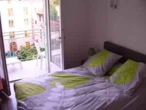 ein Bett mit einer grünen und weißen Bettdecke und einem Fenster in der Unterkunft Résidence Espinchal in Massiac