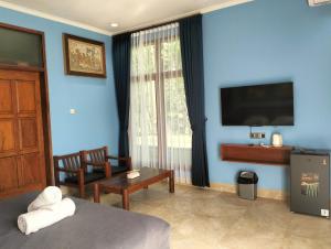 a bedroom with a blue wall with a bed and a tv at Villa Biyu siyu in Ubud