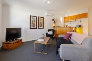 Una sala de estar con un sofá y un televisor. en Central Bendigo Apartment - CBD, en Bendigo