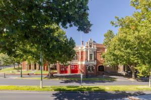 Un viejo edificio de ladrillo rojo en una calle con árboles. en Central Bendigo Apartment - CBD, en Bendigo