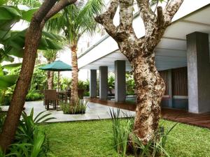 a courtyard with palm trees and a table and umbrella at Mitra Bandung Hotel in Bandung