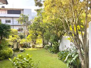 einen Garten mit grünem Gras und Bäumen sowie ein Gebäude in der Unterkunft Kandy - City Hideout Villa in Kandy
