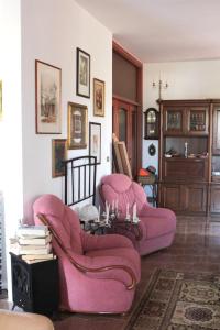 een woonkamer met roze stoelen en een tafel bij Alchimia tra suoni e colori in Marina di Mancaversa
