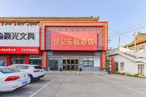 Un edificio con coches aparcados delante. en Kunlun Leju Business Hotel Kaifeng Gulou, en Kaifeng