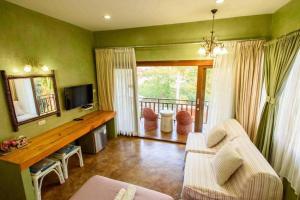 a living room with a couch and a television at Baan Parinda (Pompom Home) in Pran Buri