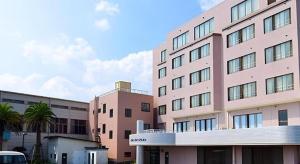 a large pink building with palm trees in front of it at Hotel New Otsuka in Shirako