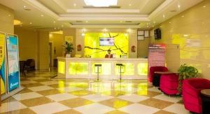 a lobby with red chairs and a yellow wall at GreenTree Alliance Ningbo Cixi Guanghaiwei Industrial Park East Area Hotel in Ningbo