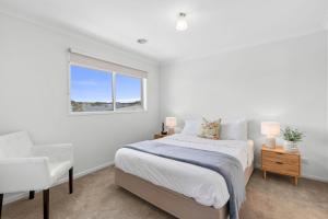 Un dormitorio blanco con una cama y una silla. en 3BR Retreat Mount Duneed, en Grovedale 7 fotos más