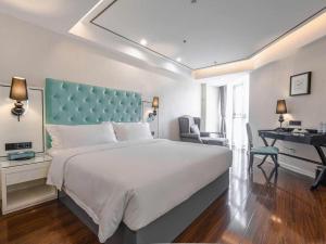 1 dormitorio con 1 cama grande con cabecero azul y escritorio en Xana Lite Anqing Yuexi Swan Squre Branch, en Yuexi 264 fotos más