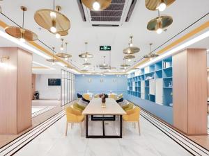 an office lobby with a table and yellow chairs at Magnotel Hotel Jining Yanzhou Metro Station Jiuxianqiao South Road in Jining