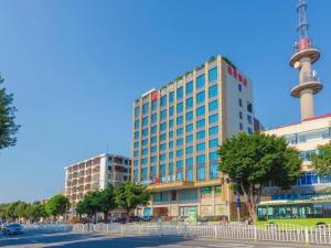 a tall building with a tv tower in the background at Borrman Hotel Zhanjiang Shimao Building High-speed Railway Station in Zhanjiang