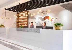 deux personnes assises à un comptoir dans un hall dans l'établissement Borrman Hotel East Huai'an Railway Station Zhou 'Enlai Memorial, à Hexia