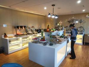 a woman standing at a counter in a kitchen at Echarm Hotel Yingshang High-speed Railway Station Wuzhou Wanhui Plaza in Fuyang