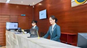 two people standing at a table with a computer at City Comfort Inn Liuzhou Baisha Bus Station Shengli Barbecue City in Liuzhou