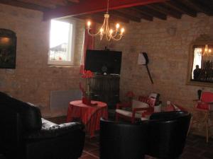 d'un salon avec des chaises, une télévision et un lustre. dans l'établissement La Ferme de Montigny (Gite), à Asnières-en-Bessin