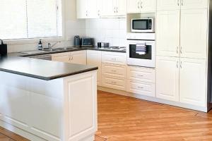 a kitchen with white cabinets and a stove top oven at Glens Parkview Apartments in Wagga Wagga