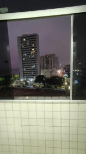 a window with a view of a city at night at Flet do condominio flet 4 rodas in Olinda
