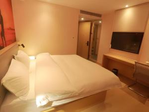 a bedroom with a white bed with a flat screen tv at Shell Hotel Chuzhou Economic Development Zone Internation Shangcheng in Chuzhou