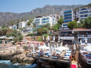 a beach with chairs and umbrellas and buildings at Sea View Hotel in Kaş