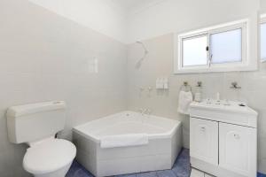 a white bathroom with a toilet and a sink at Barronstown - Pet Friendly with Fire Pit in Callala Beach +26 photos