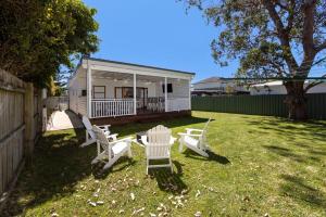 a group of white chairs sitting in a yard at Barronstown - Pet Friendly with Fire Pit in Callala Beach