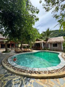 ein Pool in einem Resort mit einer Person, die schwimmt in der Unterkunft Coconut Minh Tho Homestay in Mai Châu + 30 Fotos