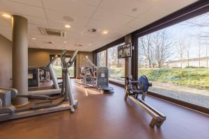 a gym with treadmills and ellipticals in front of a window at Fletcher Wellness-Hotel Stadspark in Bergen op Zoom