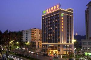 a building with a sign on top of it at night at Vienna Hotel Guangdong Shaoguan Shaonan Avenue in Shaoguan