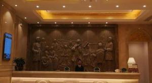 a man standing in front of a painting on a wall at Vienna Hotel Guangdong Zhaoqing Sihui Tianguangxu in Zhaoqing