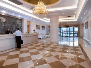 un homme debout au comptoir dans le hall de l'hôtel dans l'établissement Vienna Hotel Jiangsu Kunshan Changjiang North Road Fenghuangcheng, à Suzhou