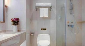 a white bathroom with a toilet and a shower at Vienna Hotel Anhui Fuyang Funan Bailing Apartment in Funan +29 photos