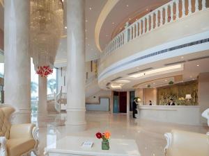 a lobby of a building with a staircase with flowers in a vase at Vienna Hotel Guangxi Wuzhou High-Tech in Wuzhou