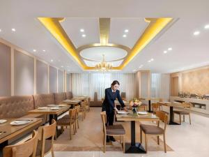 a woman sitting at a table in a restaurant at Vienna Hotel Beijing Changping Metro Station in Beijing