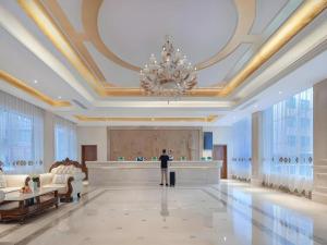 a man standing in a large lobby with a chandelier at Vienna Hotel Guizhou Hezhang in Hezhang