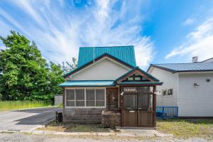 a house with a blue tin roof on a street at TARUNE in Otaru