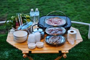 a picnic table with plates of food and drinks on it at Wintersong วินเทอร์ซอง เชียงดาว in Chiang Dao