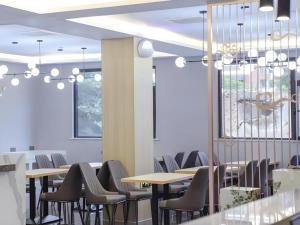a dining room with tables and chairs and windows at GreenTree Inn Express Hefei City Bus Station in Feicheng