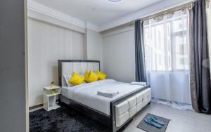 a bedroom with a bed with yellow pillows and a window at Yaya suites in Nairobi