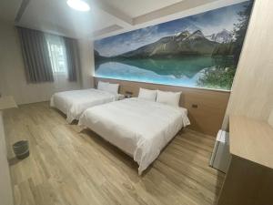 two beds in a room with a painting on the wall at Xing Yu Hotel in Mao-i-san-ts'un