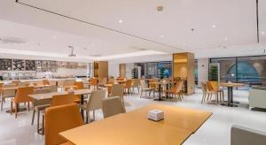 a dining room with tables and chairs and windows at City Comfort Inn Dongguan Wangniudun in Dongguan