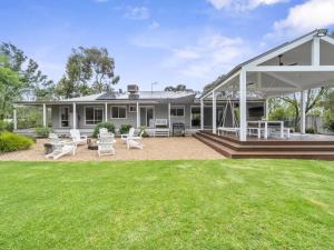 a house with a large patio with white furniture at River Retreat in Yarrawonga