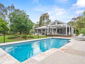 a swimming pool in front of a house at River Retreat in Yarrawonga